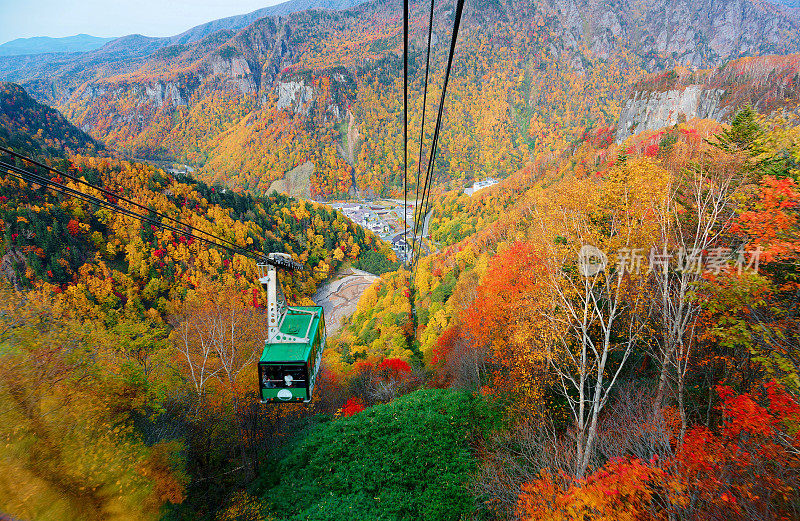 A breathtaking view from a cable car of Kurodake Ropeway flying over colorful autumn forests on the mountainside in Sounkyo Gorge (层云峡) in Daisetsuzan (大雪山) National Park, in Kamikawa, Hokkaido Japan